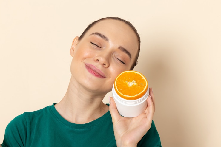 Free Photo front view young attractive female in dark green shirt holding orange on beige