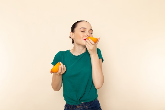 Front view young attractive female in dark green shirt holding oranges
