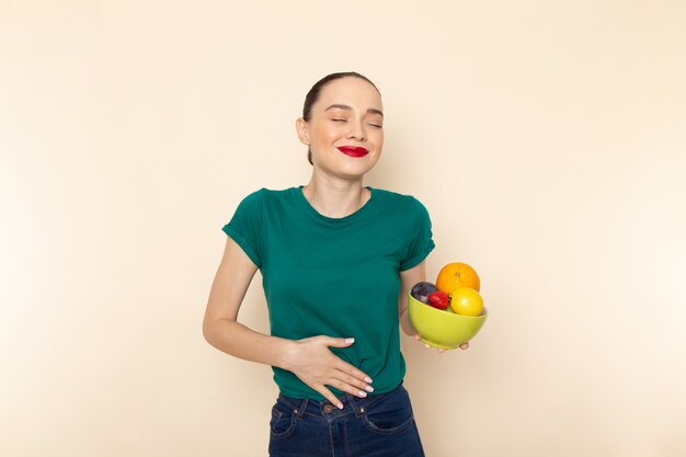 Front view young attractive female in dark green shirt holding plate with fruits with smile