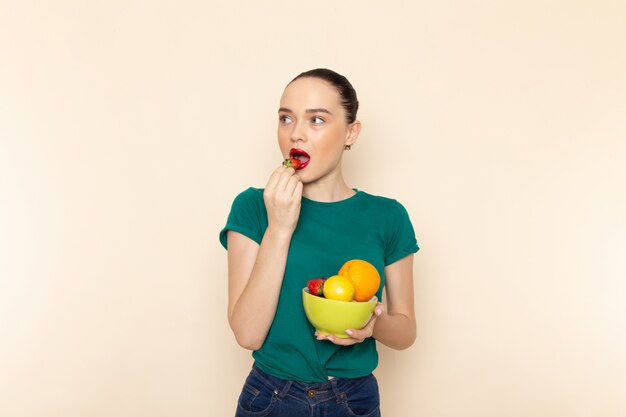 Front view young attractive female in dark green shirt holding plate with fruits