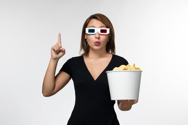 Вид спереди молодая привлекательная женщина, держащая картофельные чипсы в солнцезащитных очках d на белой поверхности