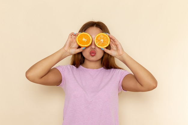 오렌지와 그녀의 눈을 덮고 분홍색 티셔츠와 청바지에 전면보기 젊은 매력적인 여성