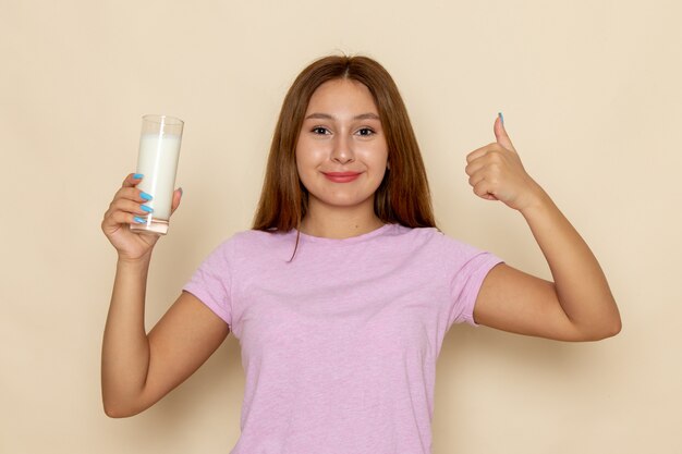 ピンクのtシャツと新鮮な冷たい牛乳を飲むブルージーンズの正面の若い魅力的な女性