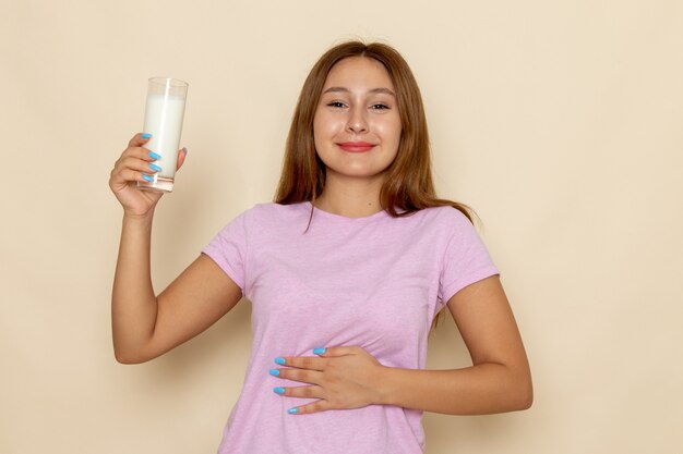 Front view young attractive female in pink t-shirt and blue jeans drinking milk with smile