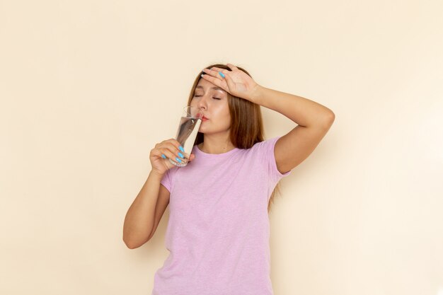 Front view young attractive female in pink t-shirt and blue jeans drinking water