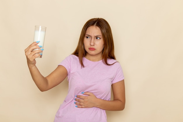 Вид спереди молодой привлекательной женщины в розовой футболке и синих джинсах, у которой болит живот из-за молока ¡¡