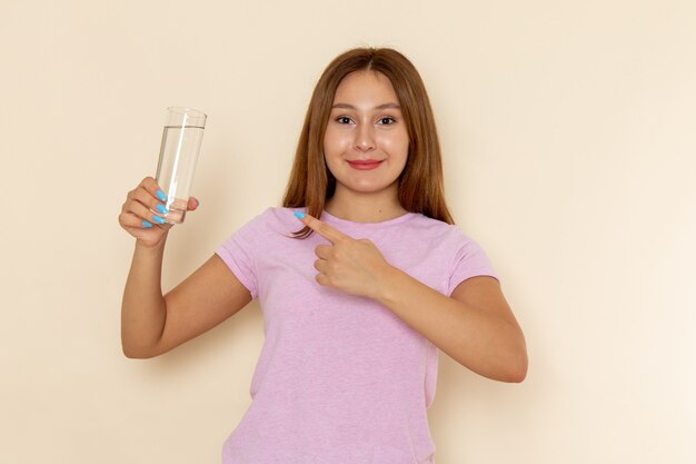 분홍색 티셔츠와 청바지 미소로 물 잔을 들고 전면보기 젊은 매력적인 여성
