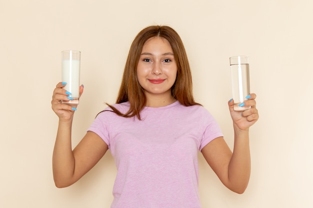 Front view young attractive female in pink t-shirt and blue jeans holding milk and water