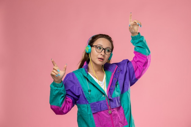 Free photo front view young attractive female in white t-shirt colored coat and listening to music dancing on pink background