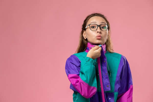 ピンクの背景にポーズをとって白いtシャツ色のコートの正面若い魅力的な女性