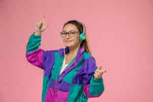 Free photo front view young attractive female in white t-shirt colored coat smiling and listening to music on the pink background