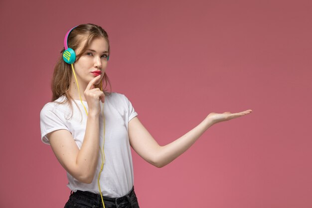 Front view young attractive female in white t-shirt listening to music on pink wall model color female young