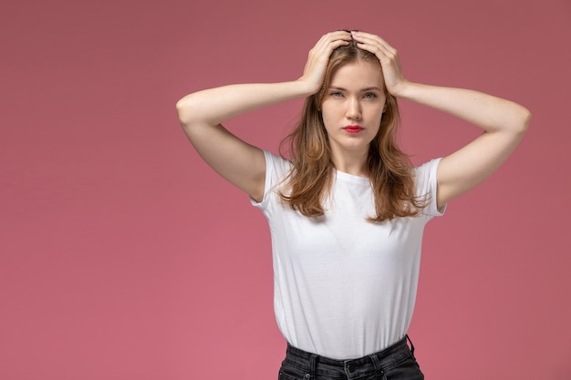 Free photo front view young attractive female in white t-shirt posing holding her head on pink wall model female pose color photo