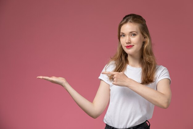 Front view young attractive female in white t-shirt posing with delighted expression on pink wall model female pose color photo