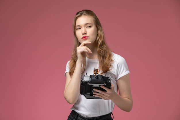 Front view young attractive female in white t-shirt posing with thinking expression on the pink wall model color female young girl