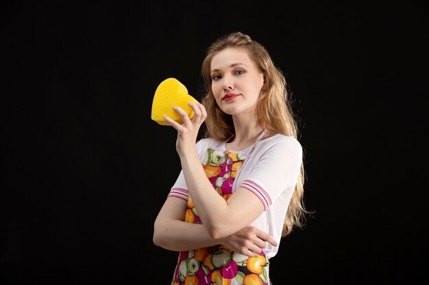 A front view young attractive girl in colorful cape smiling holding yellow heart shape on the black background love smile positivity