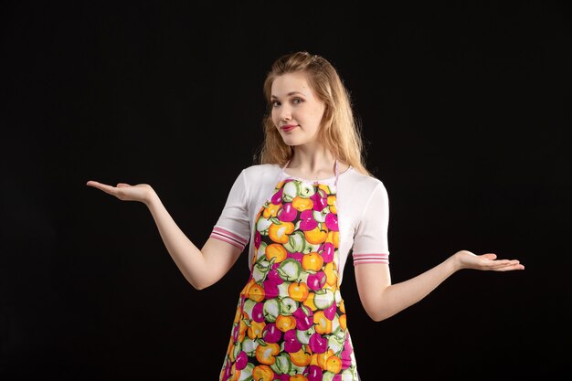 A front view young attractive girl in colorful cape smiling showing hand signs on the black background cleaning housewife