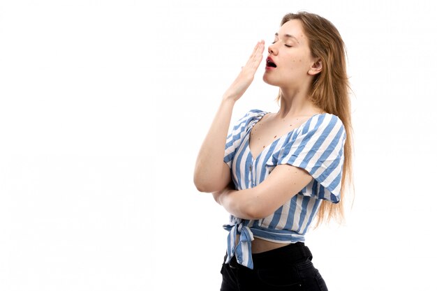 A front view young attractive girl in striped blue-white t-shirt wearing black jeans sneezing on the white