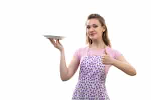 Free photo a front view young attractive housewife in pink shirt colorful cape holding white plate posing on the white background cuisine kitchen female