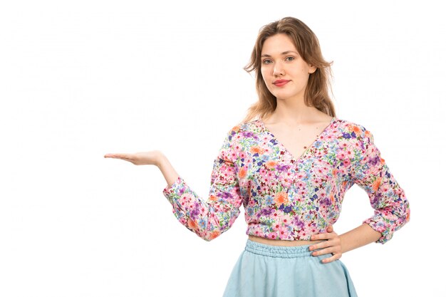 Вид спереди молодой привлекательной леди в пестрой рубашке с цветочным рисунком и синей юбке на белом