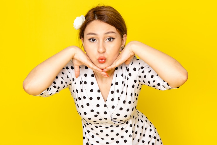 無料Photo 黄色でポーズ黒と白の水玉ドレスの正面の若い美しい女性