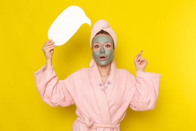 A front view young beautiful female in pink bathrobe holding white sign