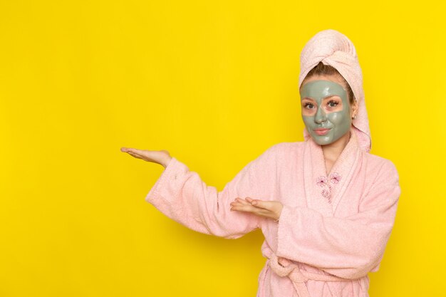 A front view young beautiful female in pink bathrobe just posing