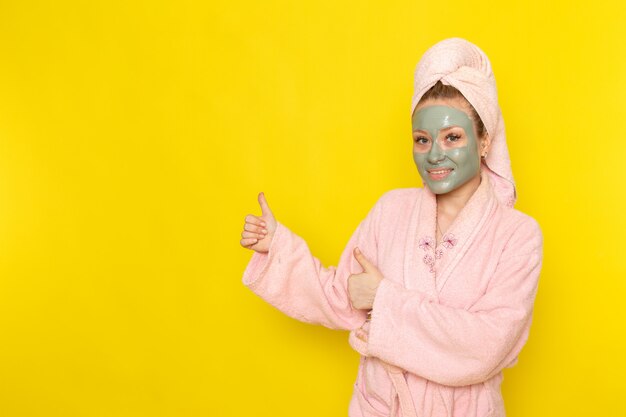 A front view young beautiful female in pink bathrobe smiling and posing