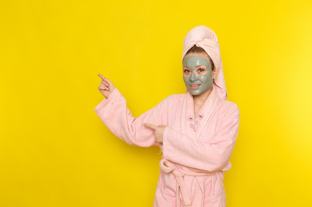 A front view young beautiful female in pink bathrobe with face-mask