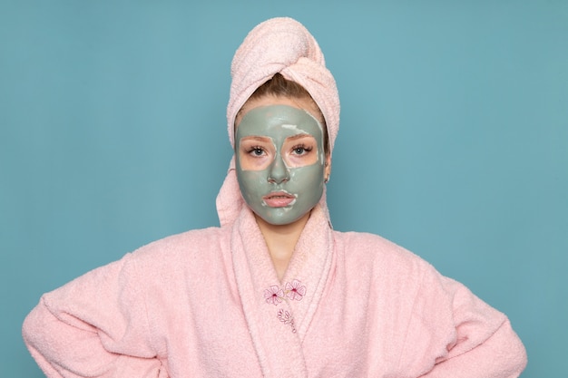 A front view young beautiful female in pink bathrobe with face mask