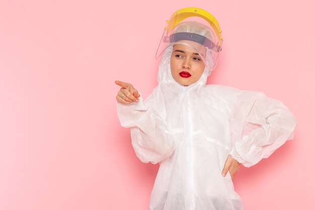 Front view young beautiful female in special white suit wearing special yellow helmet gracefully posing on the pink space special suit  girl woman