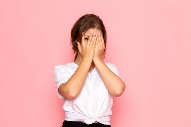 A front view young beautiful female in white shirt covering her face