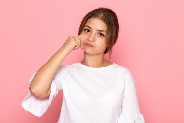 A front view young beautiful female in white shirt pulling off her cheek