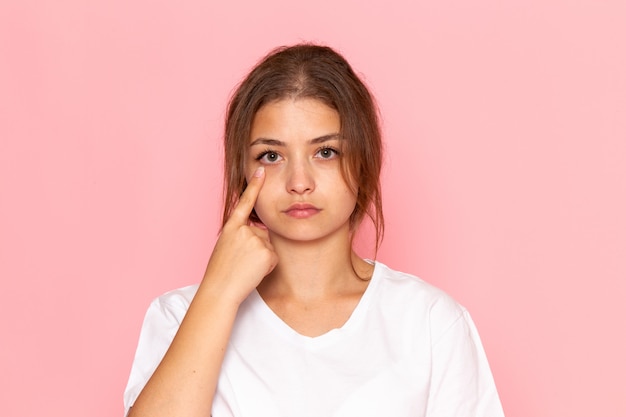 A front view young beautiful female in white shirt showing her eye