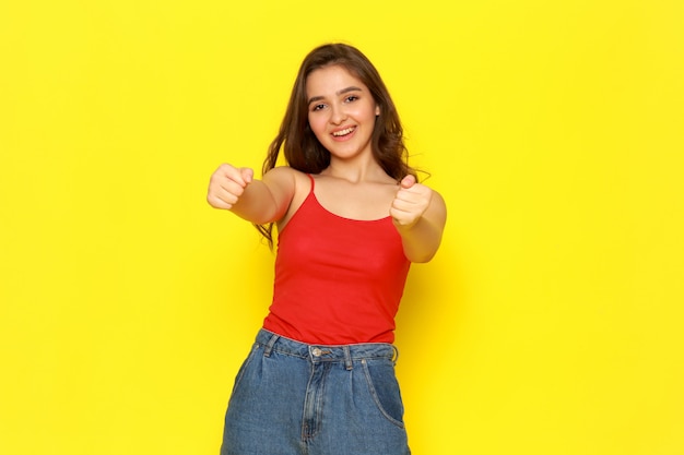 A front view young beautiful girl in red shirt and blue jeans posing with excited delighted expression