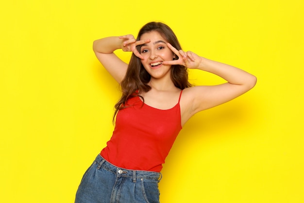 A front view young beautiful girl in red shirt and blue jeans posing with funny expression