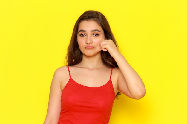 A front view young beautiful girl in red shirt and blue jeans pulling off her cheek