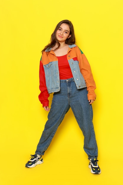 A front view young beautiful girl in red shirt coat and blue jeans posing with smiling expression