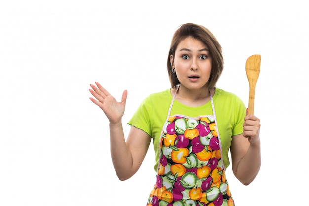 A front view young beautiful housewife in green shirt colorful cape posing suprised excited expression happy on the white background house female kitchen