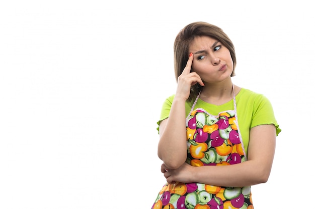 A front view young beautiful housewife in green shirt colorful cape thinking hesitated