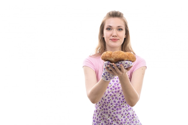 A front view young beautiful housewife in pink shirt colorful cape happy smiling holding bakeries smiling