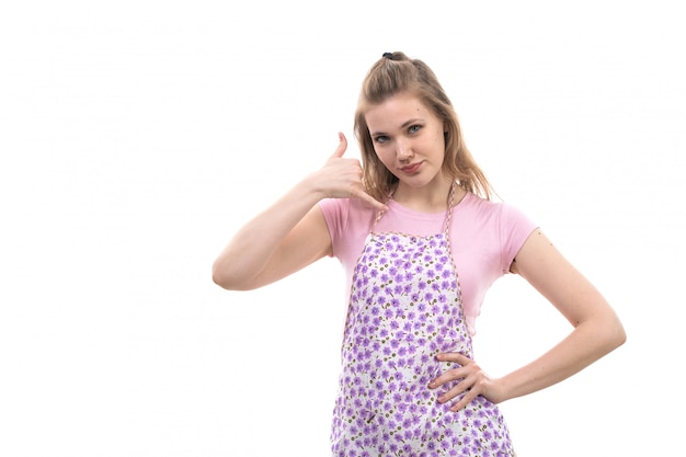 A front view young beautiful housewife in pink shirt colorful cape showing phone talk sign