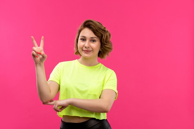 A front view young beautiful lady in acid colored shirt black trousers posing smiling