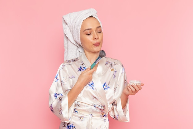 A front view young beautiful lady in bathrobe doing make-up