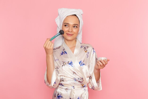 A front view young beautiful lady in bathrobe doing make-up