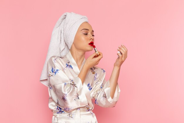 A front view young beautiful lady in bathrobe doing make-up