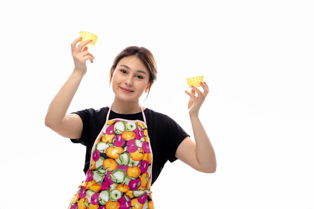 Вид спереди молодая красивая дама в черной рубашке и красочной накидке с желтыми маленькими сковородками
