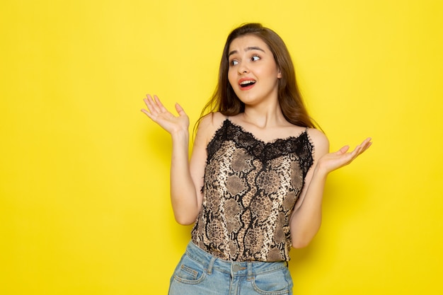 A front view young beautiful lady in brown blouse and blue jeans posing