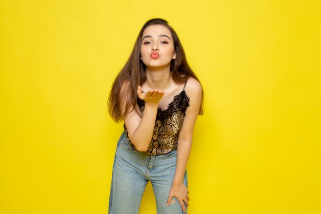 A front view young beautiful lady in brown blouse and blue jeans senidn kisses