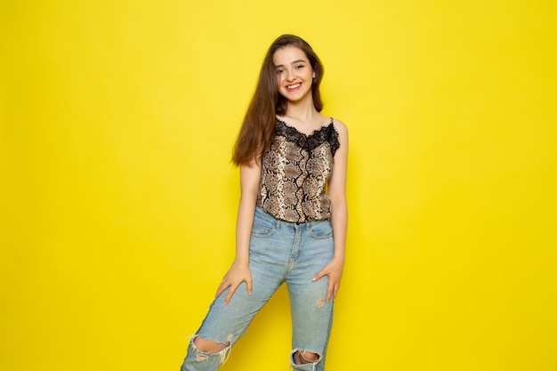 A front view young beautiful lady in brown blouse and blue jeans smiling posing